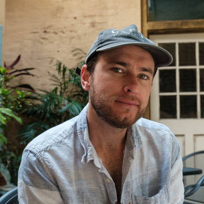 man with baseball cap smiles at camera